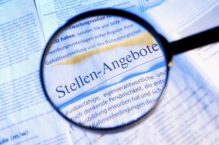 Stellenangebote in der Zeitung, mit einer Lupe darüber