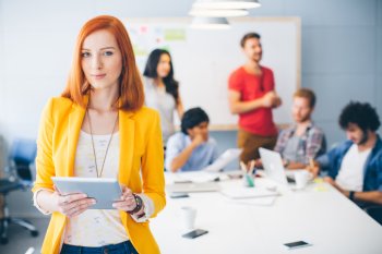 BWL Studium BWL-Studentin steht mit Tablet im Vordergrund, Lerngruppe im Hintergrund vor Whiteboard