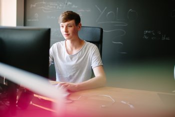 BWL-Student sitzt vor einer Tafel am Computer