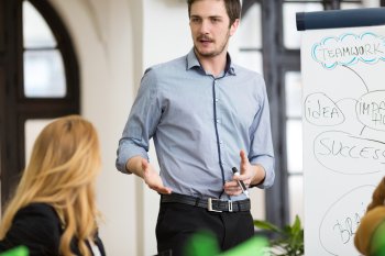 Junger Manager steht an Whiteboard und hält Vortrag