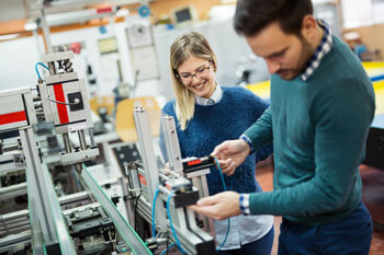 Eine junge Frau und junger Mann arbeiten mit einem technischen Gerät.