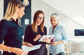 Drei Eventmanagerinnen stehen zusammen und diskutieren über etwas