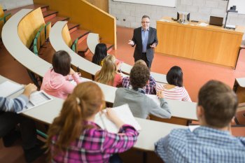 Dozent steht in Hörsaal vor einigen Studierenden