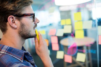 Grafikdesign Studium Inhalte Grafikdesign Studium steht vor Wand mit Post-Its und überlegt