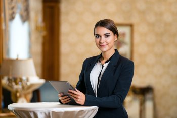 Hotelmanagerin steht mit Unterlagen an Stehtisch im Hotel