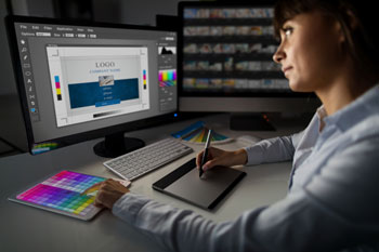 Eine Frau arbeitet an einem Computer mit Farbmustern und Grafiktablet an einem Design.