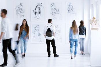 Sechs Personen betrachten Bilder in einer Ausstellung.
