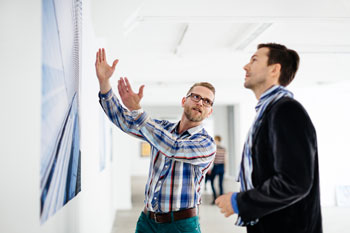 Zwei Männer betrachten und diskutieren ein Kunstwerk in einer Ausstellung.