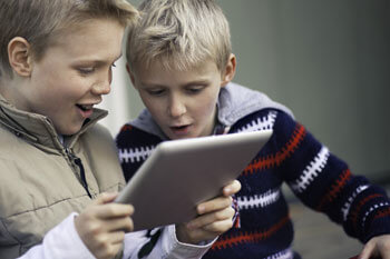 Zwei Jungen schauen auf Tablet.