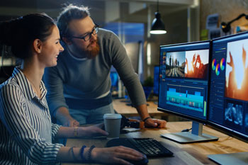 Ein junger Mann und eine junge Frau arbeiten mit Computern am Tonschnitt.