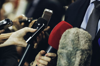 Hände halten Mikrofone in Richtung eines Mannes.