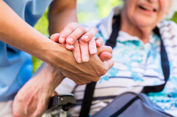 Ein Pfleger hält die Hände einer älteren Frau.