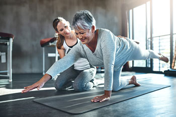 Physiotherapeutin macht Übungen mit einer älteren Frau.