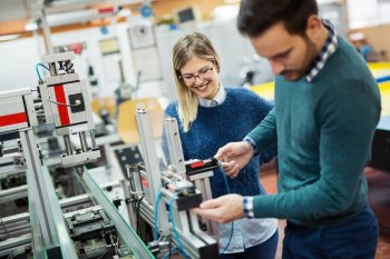 Zwei junge Produktionstechniker stehen an einer Maschine