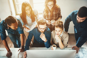 Sechs Personen schauen auf einen Computerbildschirm