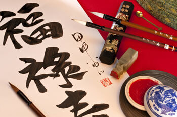 Schriftrolle mit chinesischen Schriftzeichen und Pinseln