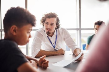 Sozialarbeiter sitzt mit Kindern am Tisch