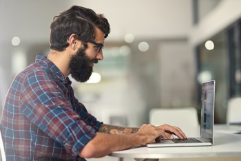 Junger Mann sitzt an Laptop