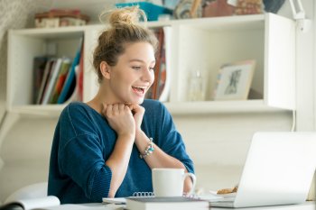 Junge Frau sitzt vor Laptop und freut sich