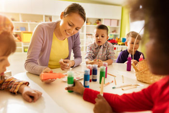 Eine Sozialpädagogin betreut eine Gruppe kleiner Kinder.