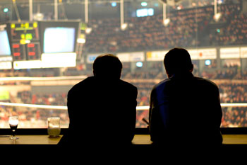 Zwei Männer sitzen in einer Lounge in einem Stadion.