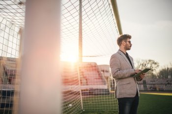 Sportmanager steht mit Tablet in der Hand in leerem Tor