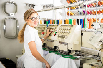 Eine Frau bedient eine Maschine in einer Textilfabrik.