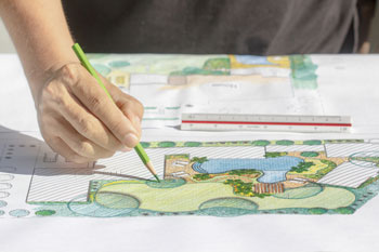 Eine Hand zeichnet einen Landschaftsbauplan.
