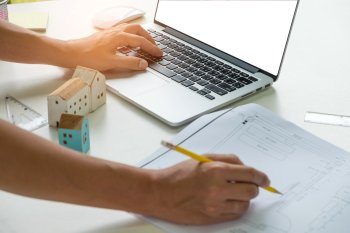 Eine Hand auf Laptop, die andere macht sich handschriftliche Notizen