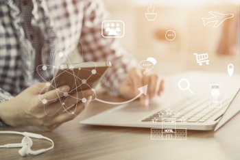 Wirtschaftsinformatik Studium Inhalte Wirtschaftsinformatik Student sitzt an Laptop und hat Smartphone in der anderen Hand, das grafisch die virtuelle Vernetzung anzeigt