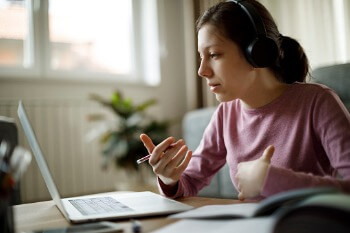 Masterstudentin sitzt mit Kopfhörern vor Laptop