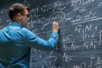 Student steht an Tafel und löst mathematische Gleichung