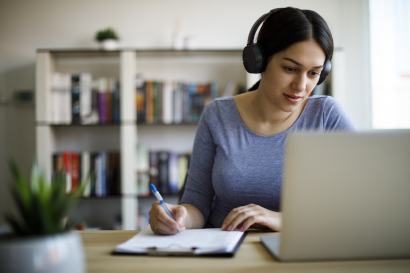 Junge Frau mit Kopfhörern vor einem Laptop