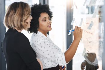 Zwei Frauen planen Strategie am Whiteboard